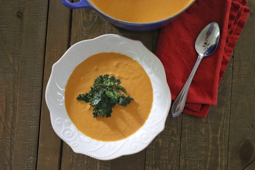 Bowl of pumpkin soup topped with kale chips