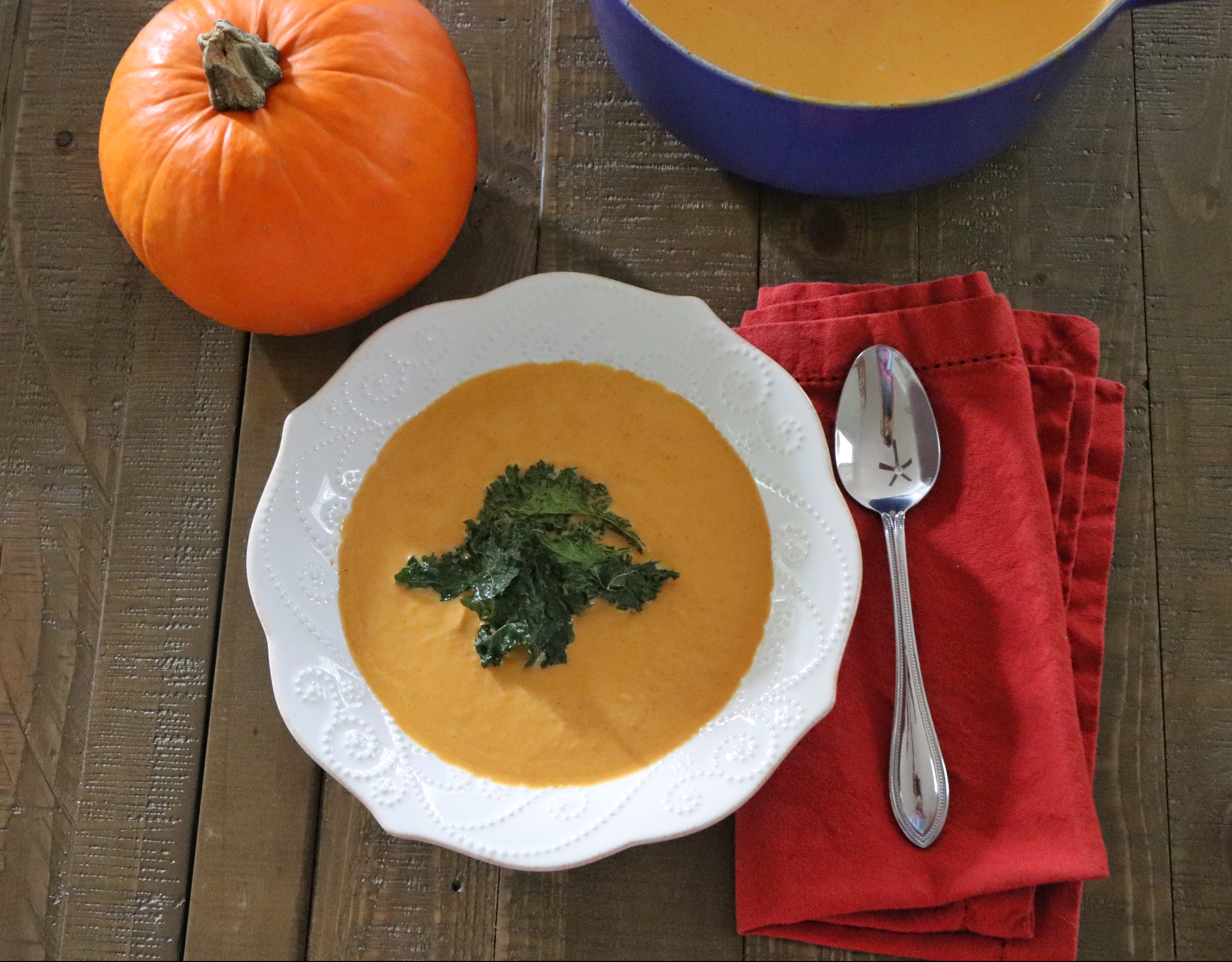 Bowl of pumpkin soup topped with kale chips