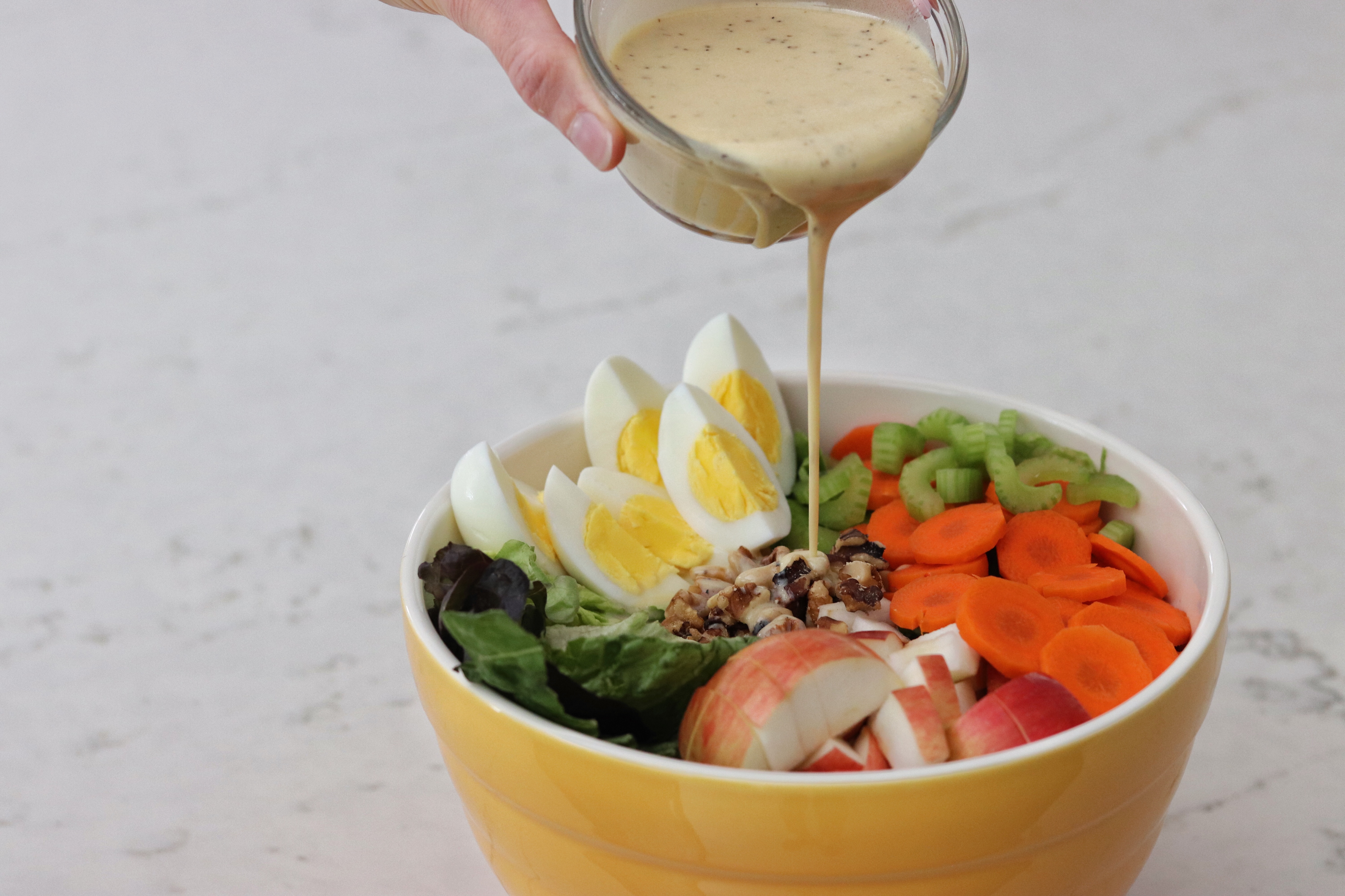 Pouring Honey Mustard Dressing over a bowl of Fall Salad with Boiled Eggs