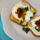 Savory French toast topped with fried eggs, salsa, and chopped parsley