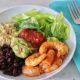 Baja Shrimp Bowl with romaine lettuce, quinoa, black beans, shrimp, salsa, and guacamole