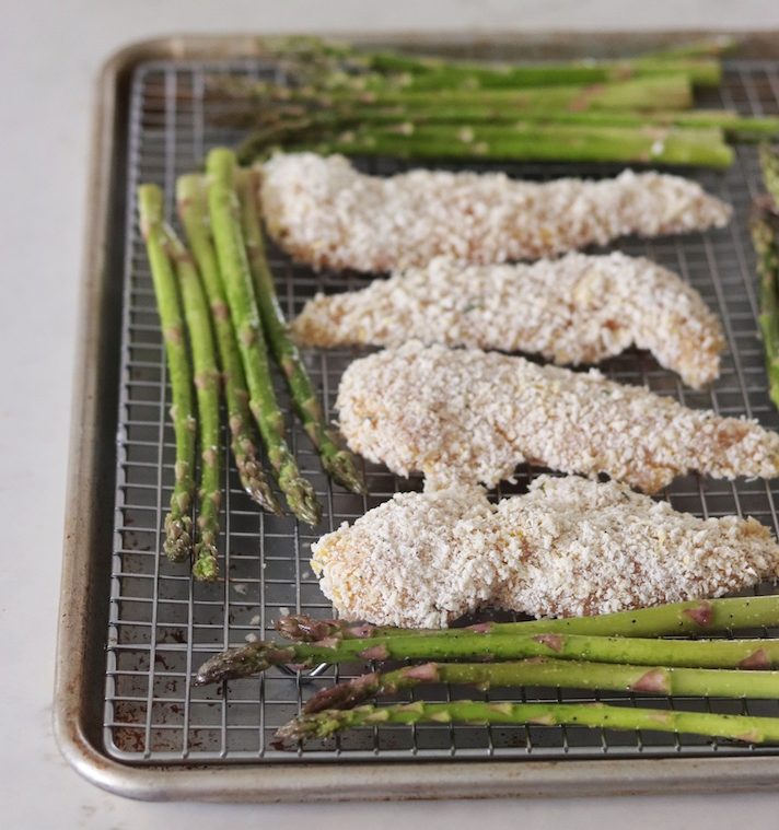 A sheet pan with crispy coated chicken and asparagus