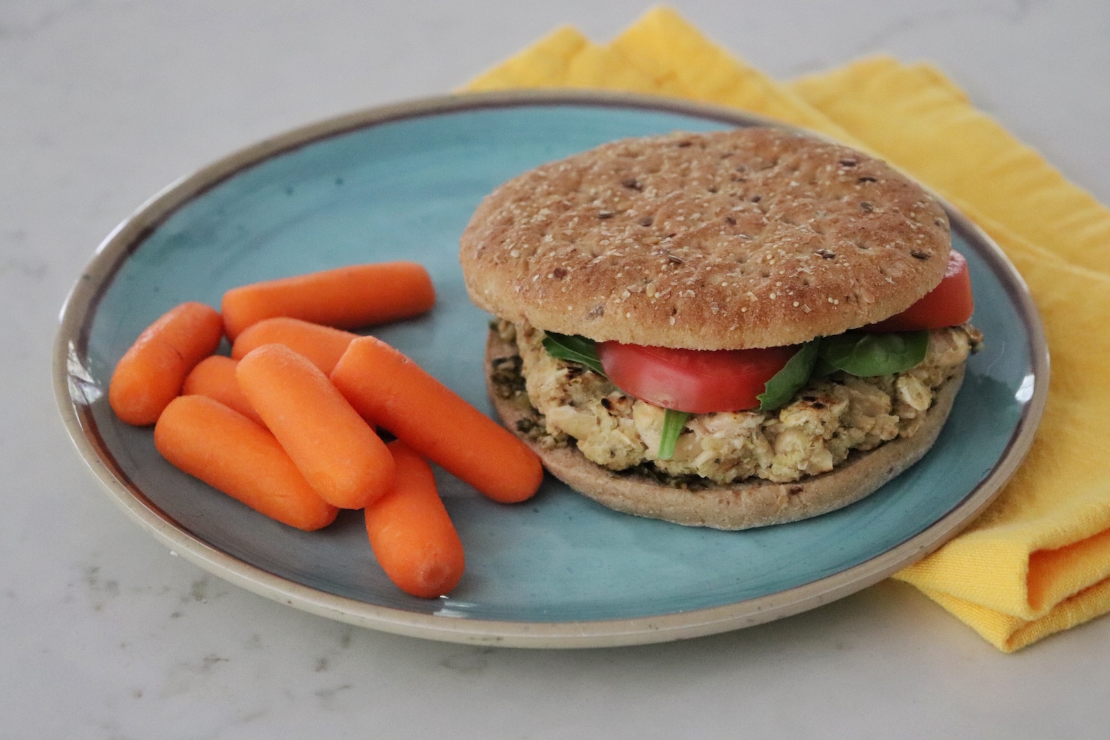 Flaxseed Quinoa and White Bean Burger on a blue plate with carrots